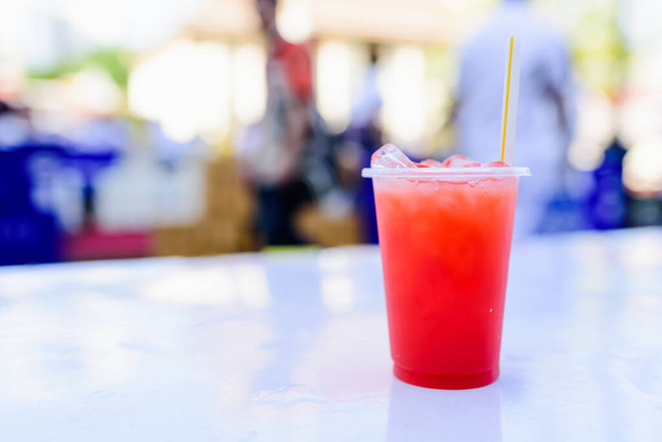 Sommergetränk oder Cocktails: hausgemachter Erdbeersaft und Eis im Plastikglas. - Foto, Bild