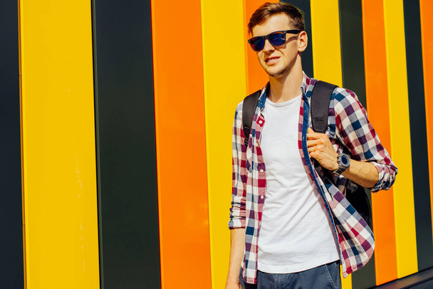 Excited happy young hipster man, in sunglasses, in trendy clothes, with half-sleeve, posing isolated on colorful bright background. People lifestyle concept - Fotó, kép