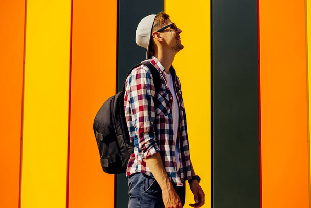 Side view of an excited young hipster guy in trendy clothes, with half-sleeve, posing isolated on a colored background. People lifestyle concept - Foto, Imagem