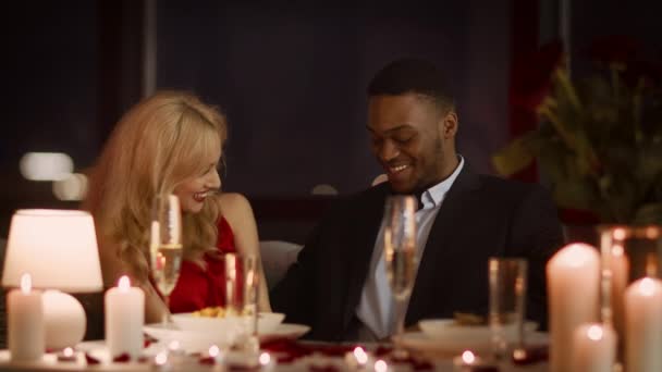 Szczęśliwa, zróżnicowana para Flirtuje i śmieje się przy kolacji w restauracji - Materiał filmowy, wideo