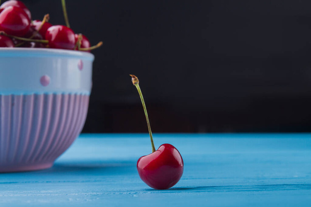 Close-up fresh ripe cherry on blue wooden desk. - Photo, Image