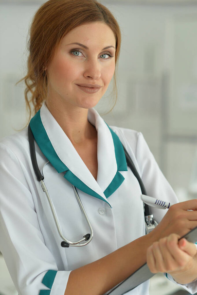 Portrait of smiling female doctor showing clipboard in hospital  - Fotoğraf, Görsel