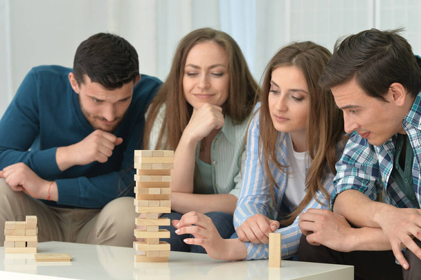 men and  women sitting at table and playing with wooden blocks - Foto, Imagem
