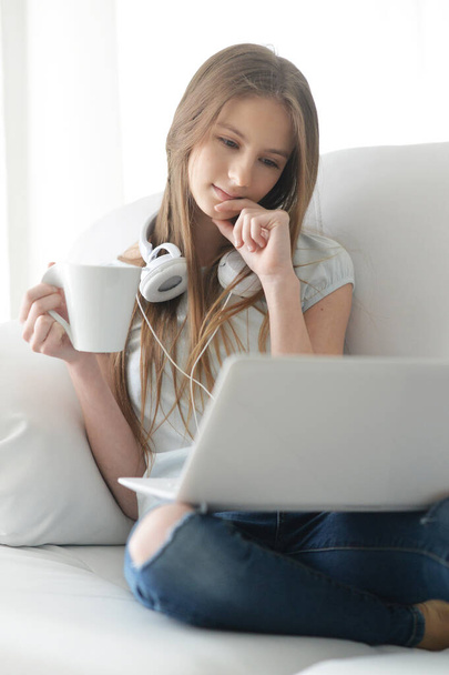  cute girl  with headphones  using  laptop on sofa at home  - Foto, Imagem