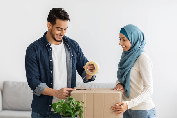 Kaunis nuori muslimipari muuttaa uuteen taloon, pakkaa tavaraa - Valokuva, kuva