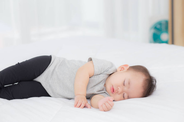 Πορτρέτο της ασιατικής κοριτσάκι κοιμάται στο κρεβάτι στην κρεβατοκάμαρα στο σπίτι, νεογέννητο υπνάκο με ζεστό και να χαλαρώσετε, αθωότητα βρέφος στο κρεβάτι, χαρούμενος μωρό χαριτωμένο, ανάπτυξη του παιδιού και το συναίσθημα, σε εσωτερικούς χώρους. - Φωτογραφία, εικόνα