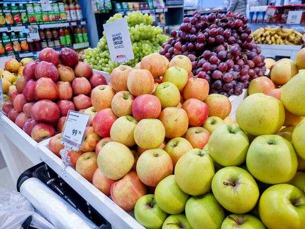 Russia, Omsk, 2 May 2021.Shelf with fruits on a farm market.Boxes with ripe various food in grocery store.Assortment of fresh raw of green, red, yellow apples on counter in the supermarket. - Foto, Bild