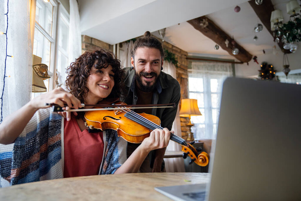 Man violin teacher helping a woman student at home - Photo, Image