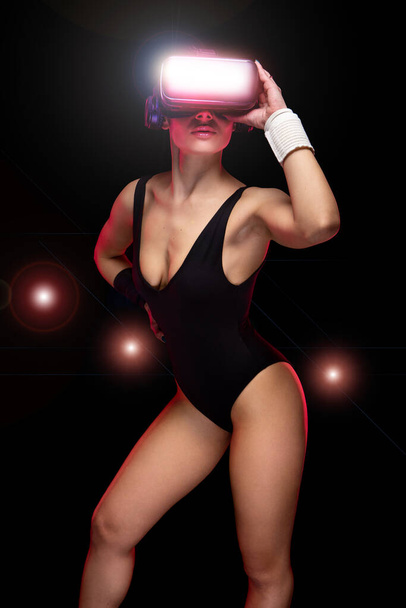 Gyönyörű aktív fiatal sportoló vonzó kaukázusi atléta képzés visel fekete tornadressz és hi tech futurisztikus szemüveg - Stúdió szépség forgatás sportos barna modell edzés során rutin - Fotó, kép