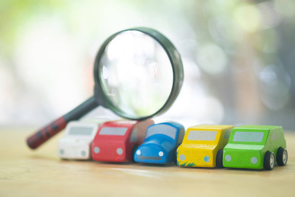 Toy car model and magnifying glass for suggesting car search. The concept of search a car to buy - Photo, image