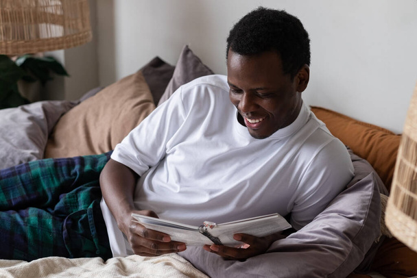 Man reading a book on his bed at home - Photo, Image
