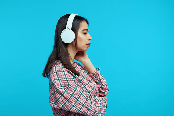 Profil des niedlichen Mädchens trägt weiße Kopfhörer hört Musik mit geschlossenen Augen - Foto, Bild