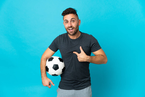 Football player isolated on blue background with surprise facial expression - Foto, Imagen