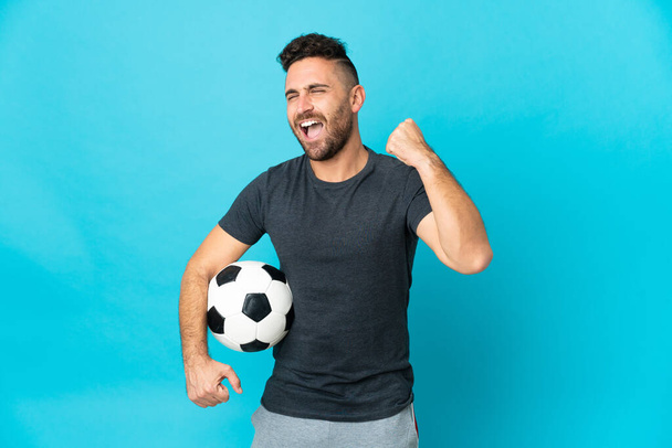 Football player isolated on blue background celebrating a victory - Foto, afbeelding