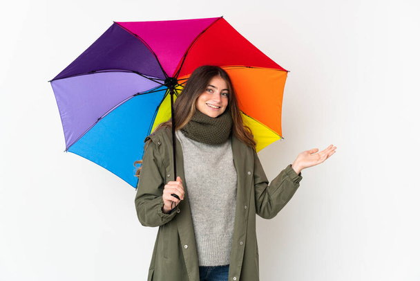 Giovane donna caucasica che tiene un ombrello isolato su sfondo bianco con espressione facciale scioccata - Foto, immagini