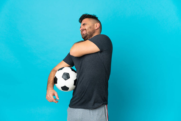Футболист изолирован на синем фоне, страдает от боли в плече за то, что сделал усилие - Фото, изображение