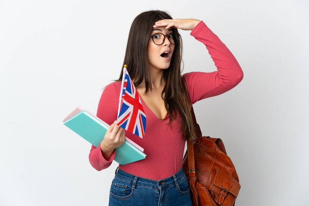 Teenager brasilianisches Mädchen mit einer britischen Flagge auf weißem Hintergrund macht Überraschungsgeste, während sie zur Seite schaut - Foto, Bild