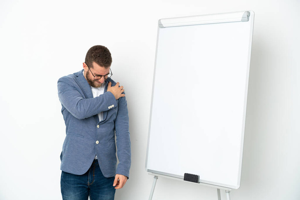 Jovem empresária fazendo uma apresentação no quadro branco isolado no fundo branco sofrendo de dor no ombro por ter feito um esforço - Foto, Imagem