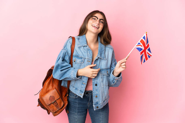 Young woman holding an United Kingdom flag isolated on pink background smiling a lot - Φωτογραφία, εικόνα