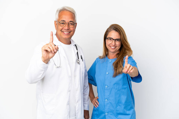 Médico y enfermera de mediana edad aislados sobre fondo blanco mostrando y levantando un dedo - Foto, Imagen