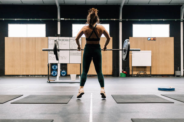 Fiatal fitness nő csinál súlyzó guggol egy tornateremben - Fotó, kép