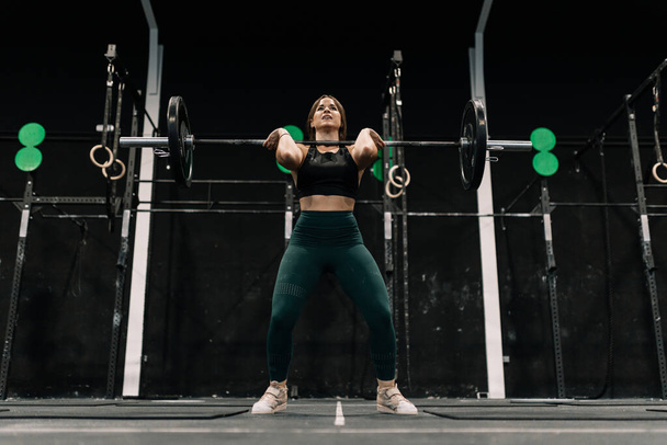 Woman performing a weightlifting exercise inside a gym - Photo, Image