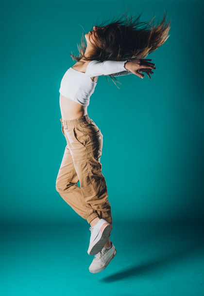 Ευέλικτη νεαρή χορεύτρια εκτελεί μια κομψή κίνηση χορού - Φωτογραφία, εικόνα