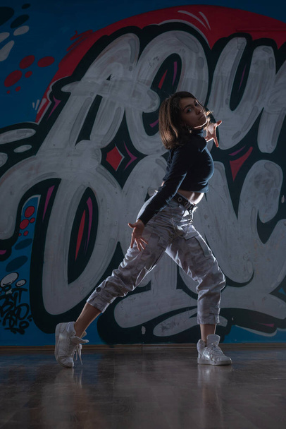 Silhouet van jonge hiphop danser (breakdancer) dansend op graffiti studio achtergrond. Contrast kleuren. - Foto, afbeelding