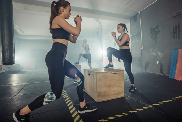 Vier sportvrouwen trainen gluten met multifunctionele training in een sportclub - Foto, afbeelding