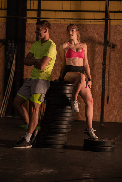 Doux et beau couple pose ensemble sur le poids dans la salle de gym - Photo, image