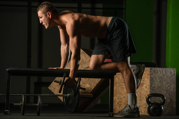 Good looking young man doing triceps dumbbell kickback exercises with his left hand - Photo, image