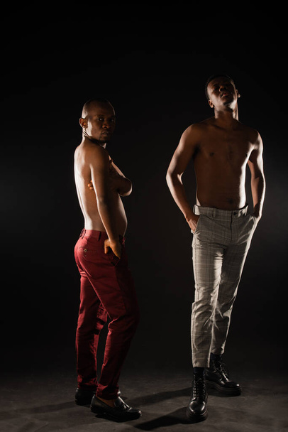 Twee afrikaanse zwarte mannen poseren topless in studio op donkere achtergrond - Foto, afbeelding