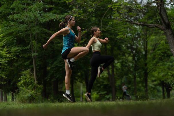 Deux filles attrayantes et bien construites sautent d'une jambe vers le haut pendant l'entraînement - Photo, image