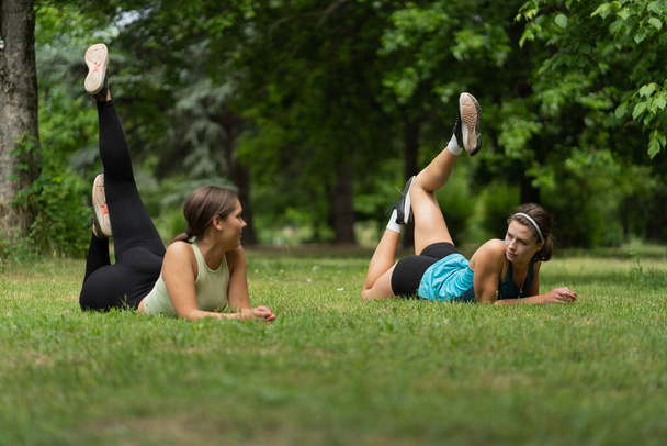 İki çekici kız yoga yaparken bir kız diğerine ders veriyor. - Fotoğraf, Görsel