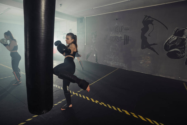 Bokser vrouw. Boksen fitnessvrouw glimlachend gelukkig dragen van zwarte bokshandschoenen. Portret van sportieve pasvorm Aziatisch model van boksschool - Foto, afbeelding