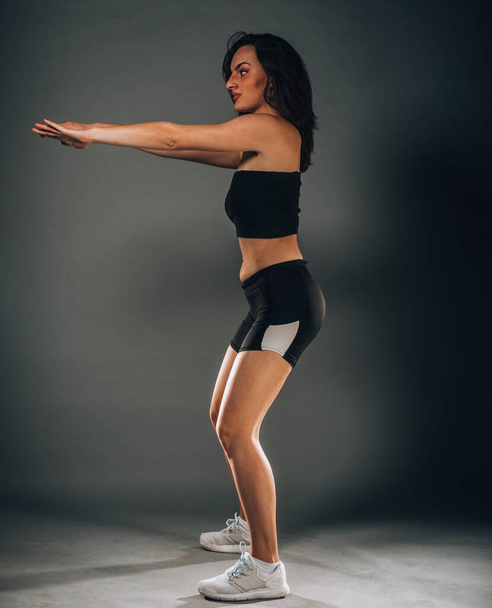 Pretty charming female training and stretching in modern dark studio - Фото, изображение