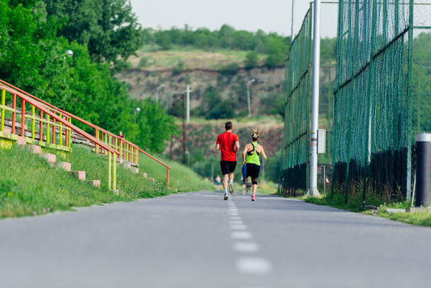 Vista desde la parte posterior de una joven pareja deportiva corriendo en el parque - Foto, Imagen