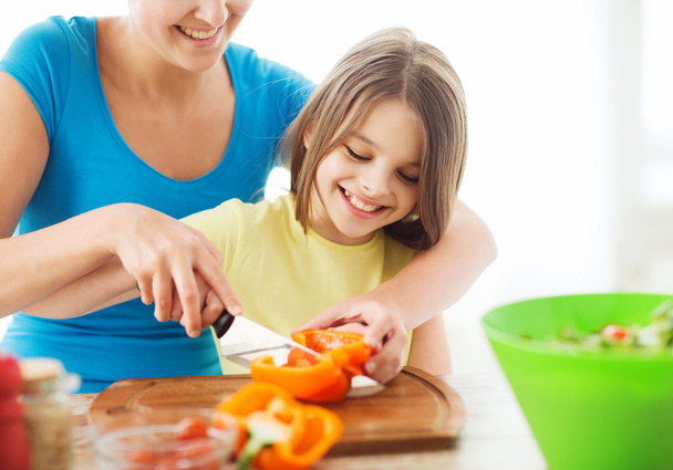 smiling little girl with mother chopping pepper - Foto, Imagen