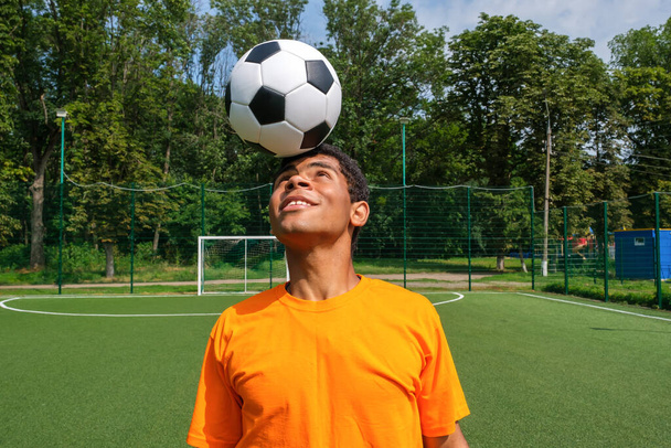 Brazilian soccer player trains and improves soccer ball control by juggling it on his head on sport ground in summer - Foto, imagen