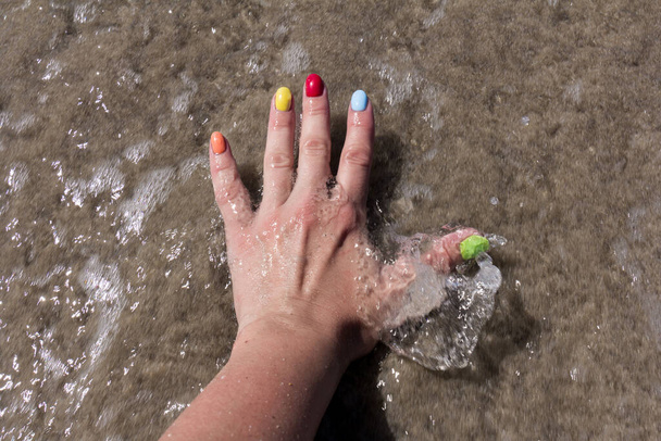 Arte de uñas de colores en la playa de arena. Esmalte de uñas colorido. concepto del descanso de verano - Foto, imagen