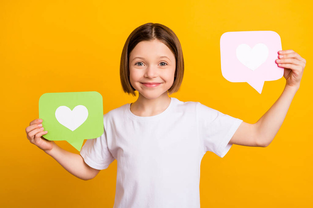 Foto portret klein schoolmeisje glimlachen houden social media icoon geïsoleerd levendige gele kleur achtergrond - Foto, afbeelding