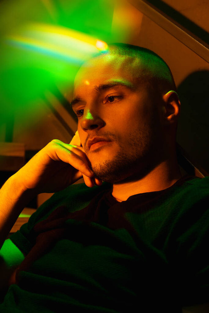 Close-up portrait of handsome young man in neon lighted room, stylish male model indoors - Foto, afbeelding