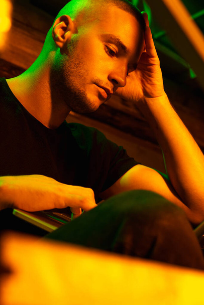 Close-up portrait of handsome young man in neon lighted room, stylish male model indoors - Photo, image