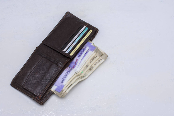 Ένα πορτοφόλι με χρήματα και πιστωτικές κάρτες σε μια λευκή επιφάνεια. Επιλεκτική εστίαση. - Φωτογραφία, εικόνα