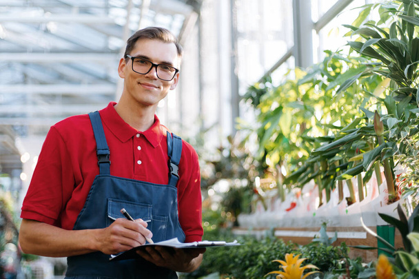 supervisor with clipboard standing among the plants in the garden center. - 写真・画像