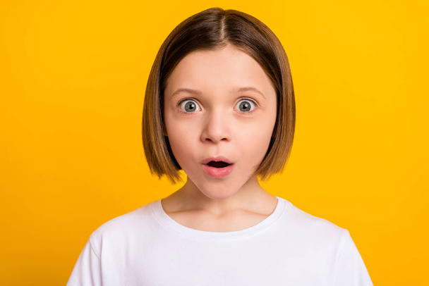 Photo portrait little girl with bob hairstyle staring amazed opened mouth isolated vivid yellow color background - 写真・画像