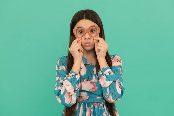 Funny teenage girl pout lips wearing heart-shaped glasses blue background, valentines day - Photo, Image