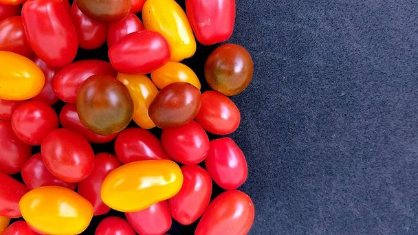 Tomates cereja de diferentes variedades em um fundo escuro para o mercado, loja, publicidade cultivada em Portugal - Foto, Imagem