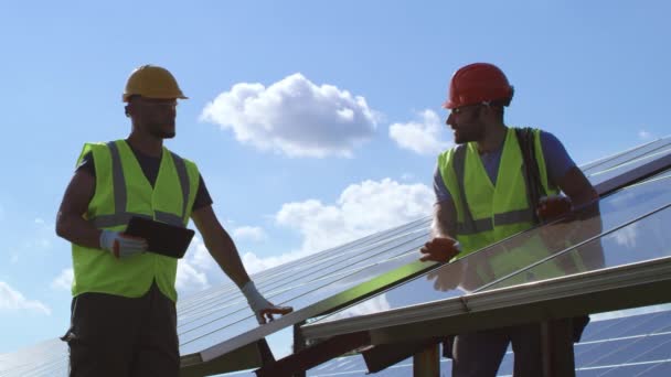 Ingenieros masculinos examinando paneles fotovoltaicos en día soleado - Imágenes, Vídeo