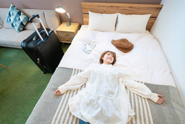 Mujer asiática relajándose en una cama de hotel - Foto, Imagen
